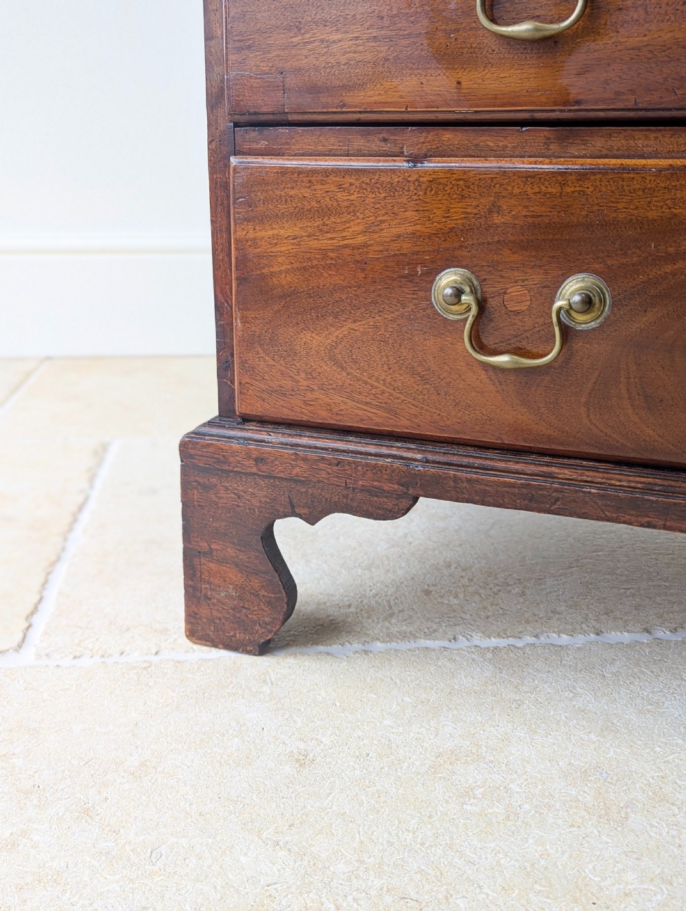 An 18th-century George III mahogany chest of drawers featuring four graduated drawers with brass swan-neck handles and bracket feet. View VII