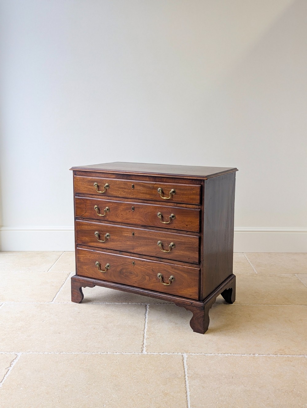 An 18th-century George III mahogany chest of drawers featuring four graduated drawers with brass swan-neck handles and bracket feet. View VIII