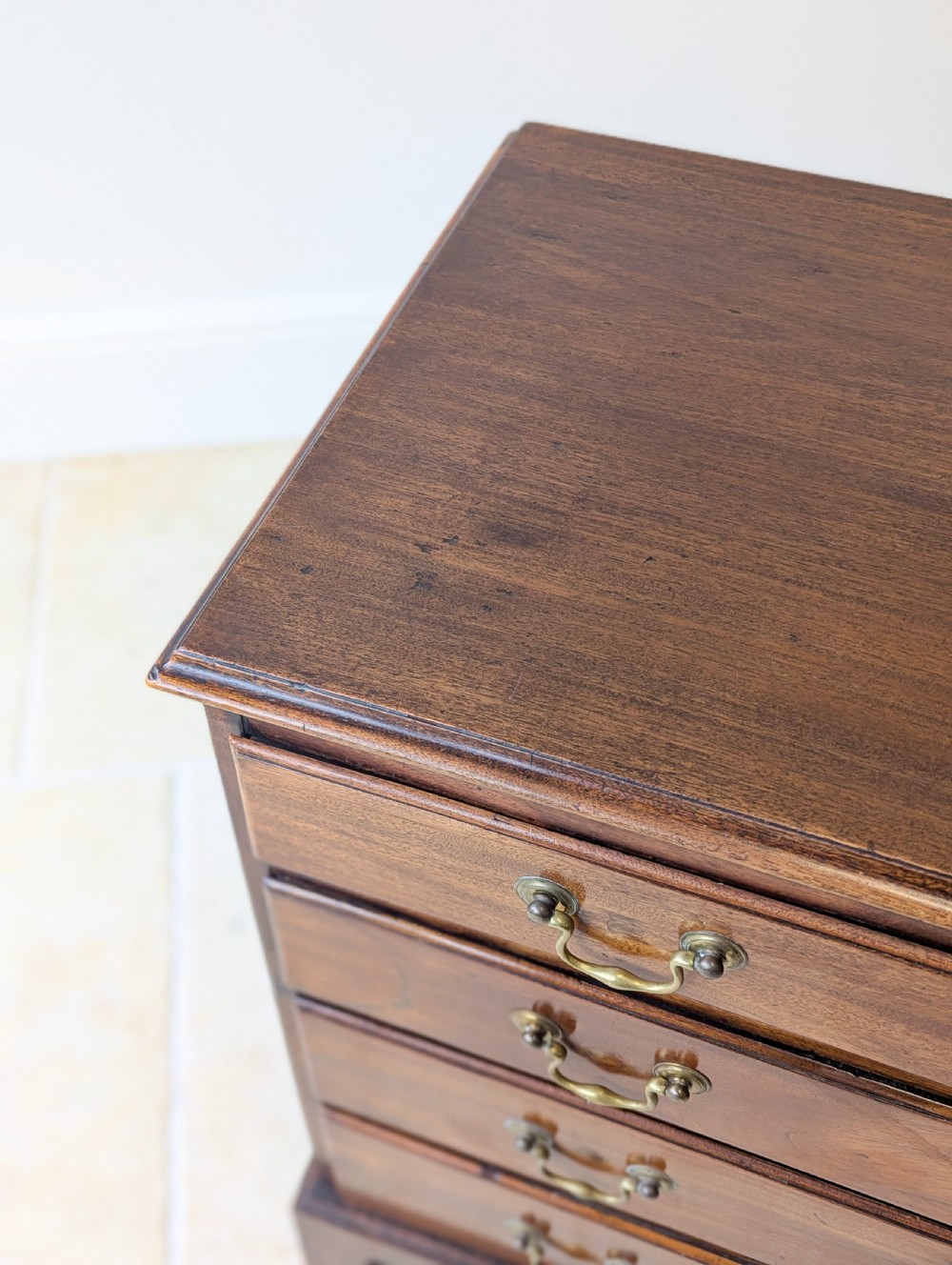 An 18th-century George III mahogany chest of drawers featuring four graduated drawers with brass swan-neck handles and bracket feet. View IX