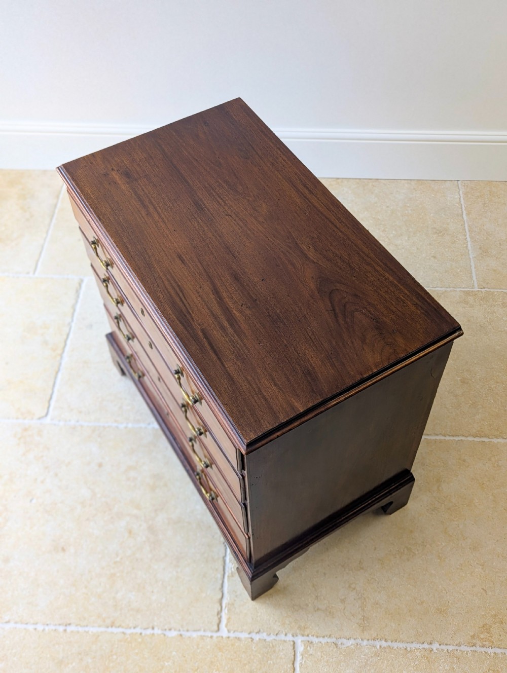 An 18th-century George III mahogany chest of drawers featuring four graduated drawers with brass swan-neck handles and bracket feet. View X