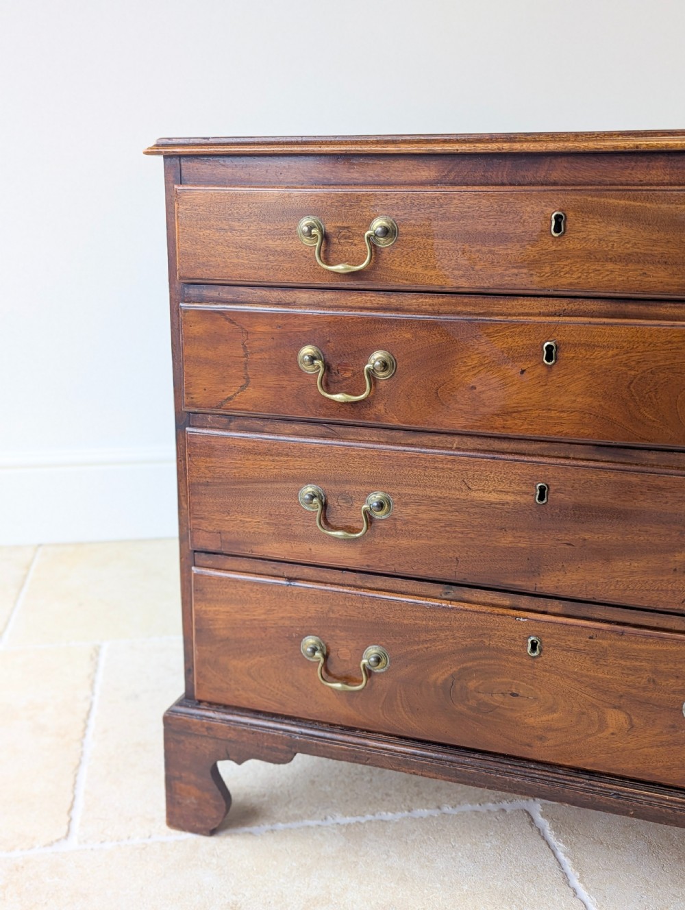 An 18th-century George III mahogany chest of drawers featuring four graduated drawers with brass swan-neck handles and bracket feet. View XI