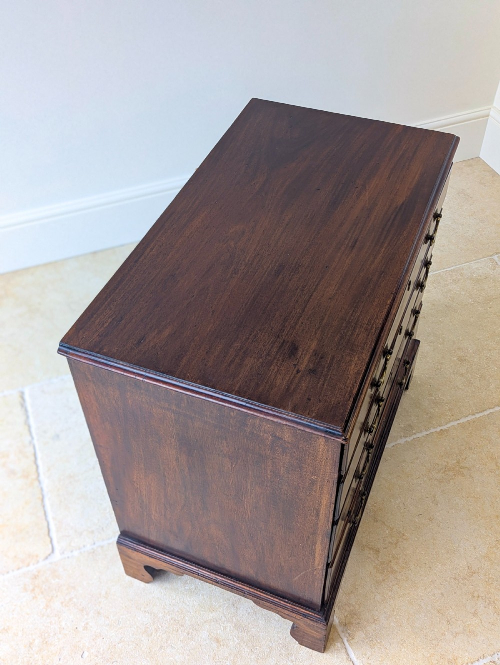 An 18th-century George III mahogany chest of drawers featuring four graduated drawers with brass swan-neck handles and bracket feet. View XII