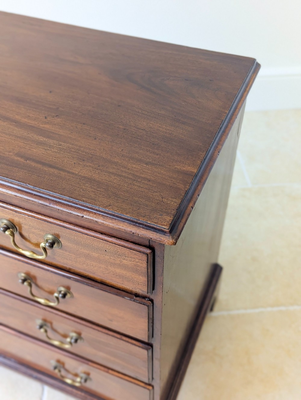 An 18th-century George III mahogany chest of drawers featuring four graduated drawers with brass swan-neck handles and bracket feet. View XIII