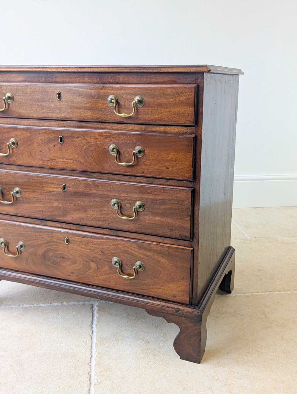 An 18th-century George III mahogany chest of drawers featuring four graduated drawers with brass swan-neck handles and bracket feet. View XV