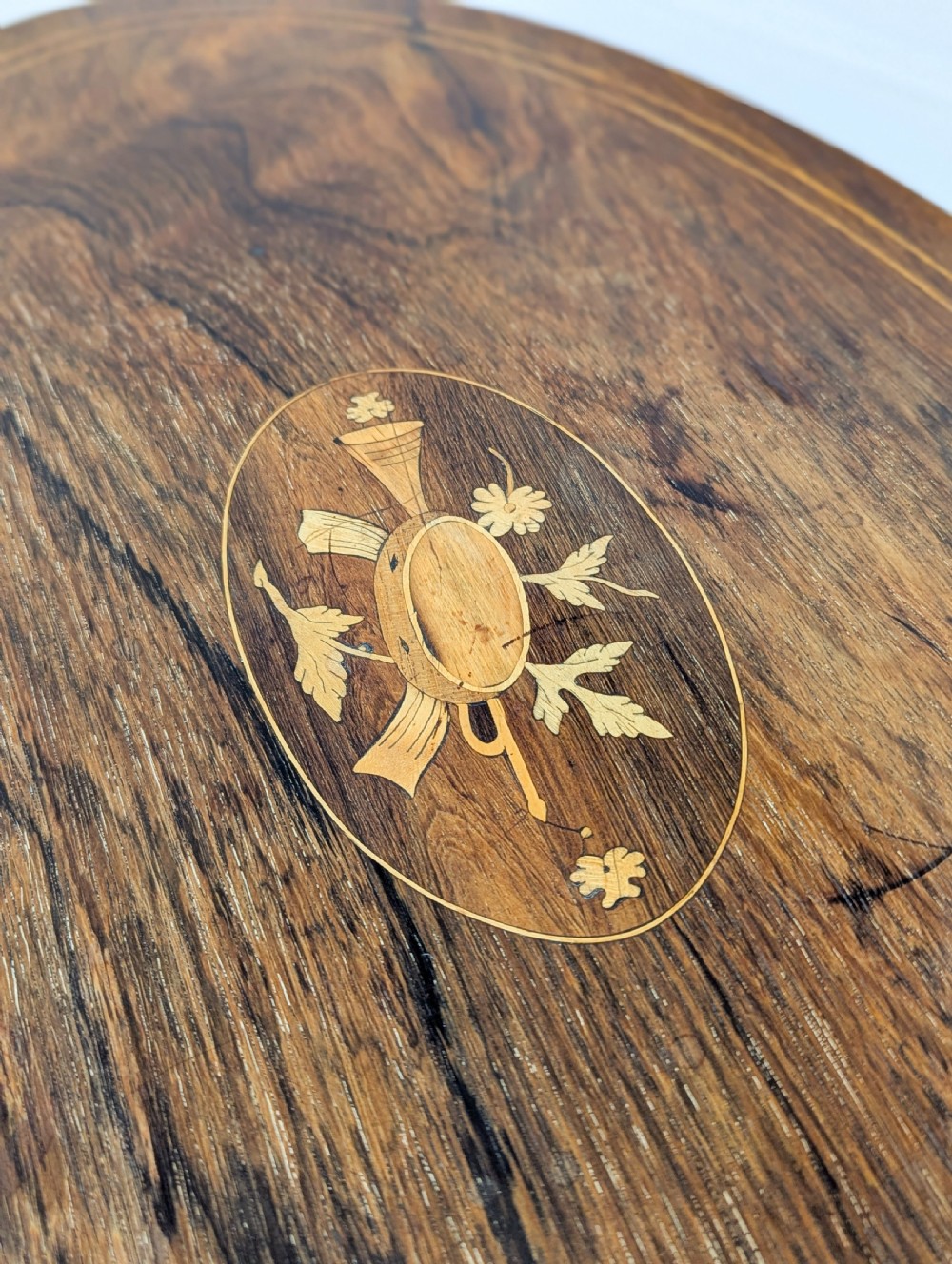 An Edwardian rosewood oval occasional table with marquetry inlay on the tabletop, slender cabriole legs, a shaped lower shelf, and brass castors. View VIII
