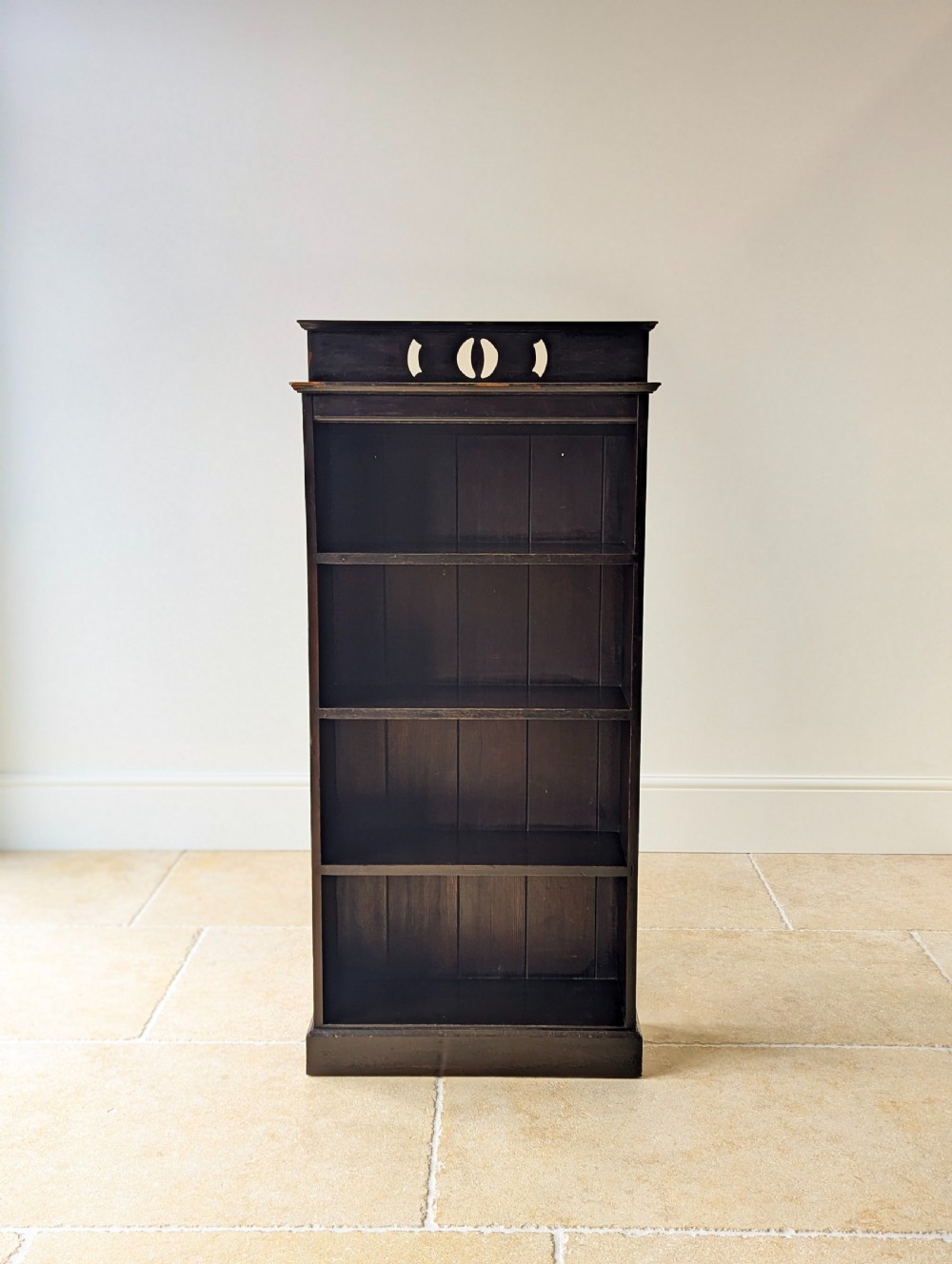 A tall, narrow late Victorian dark stained pine bookcase featuring four open shelves, a planked backboard, and a gallery top with pierced cutouts. View II