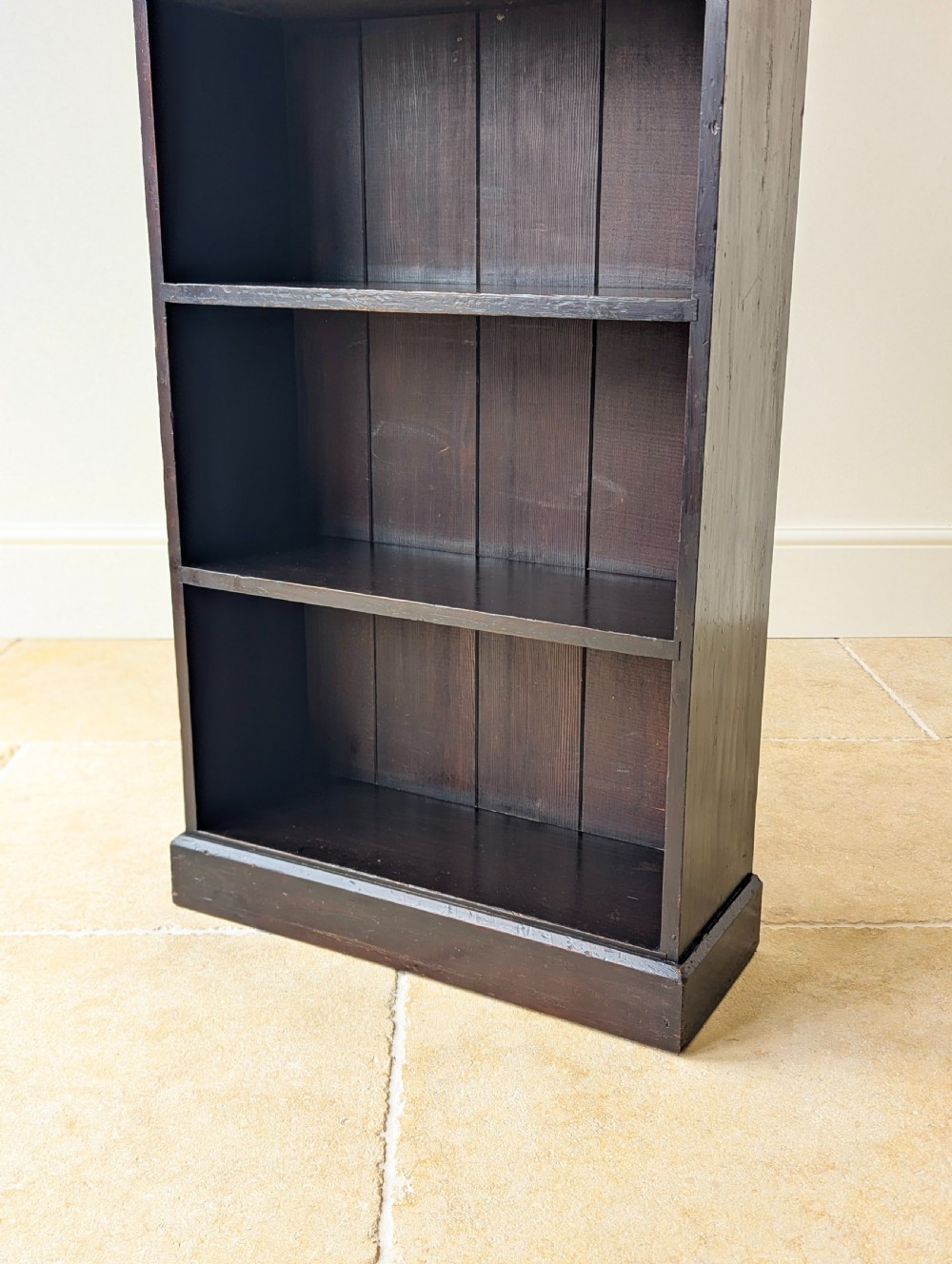 A tall, narrow late Victorian dark stained pine bookcase featuring four open shelves, a planked backboard, and a gallery top with pierced cutouts. View VI