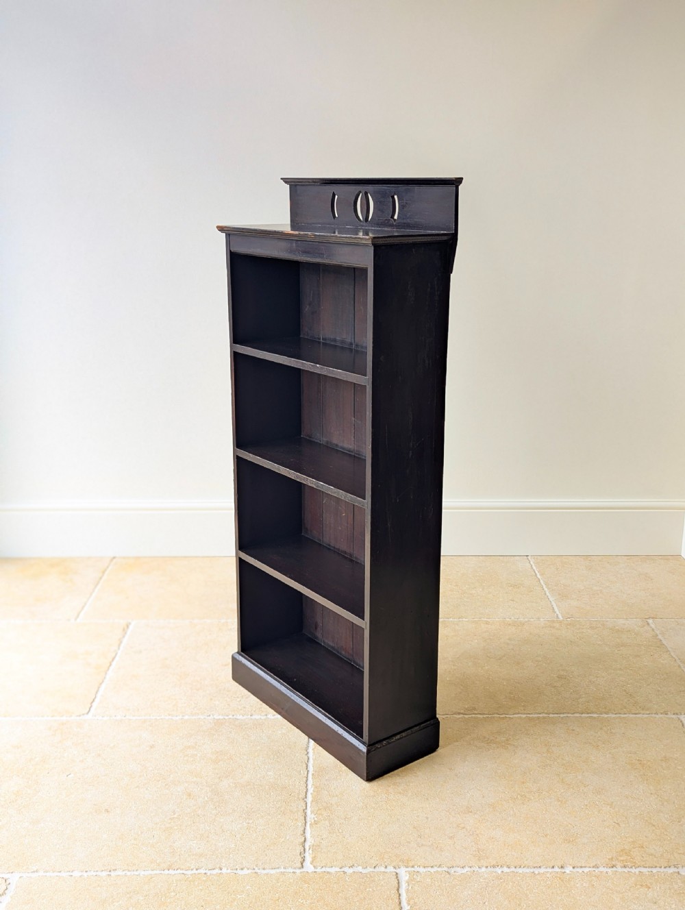 A tall, narrow late Victorian dark stained pine bookcase featuring four open shelves, a planked backboard, and a gallery top with pierced cutouts. View IX