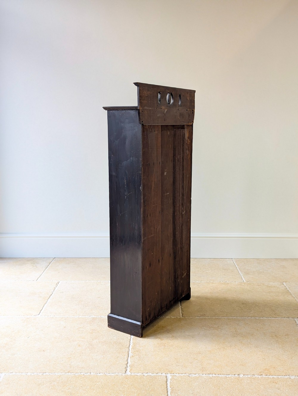 A tall, narrow late Victorian dark stained pine bookcase featuring four open shelves, a planked backboard, and a gallery top with pierced cutouts. View XIII