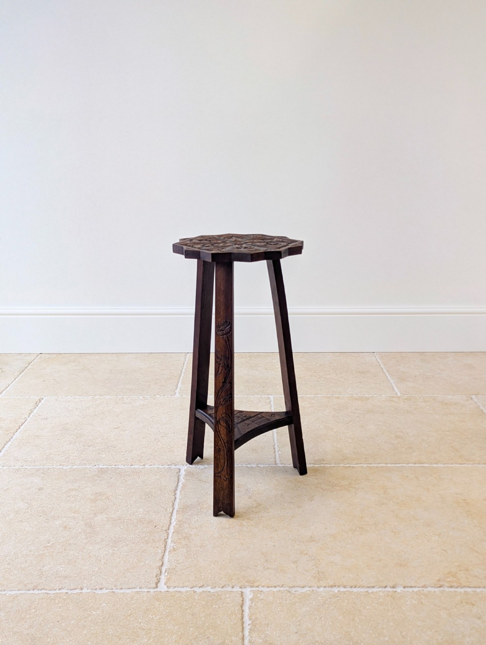 An antique dark oak three-legged occasional table featuring an octagonal carved top and triangular stretcher shelf. View VII