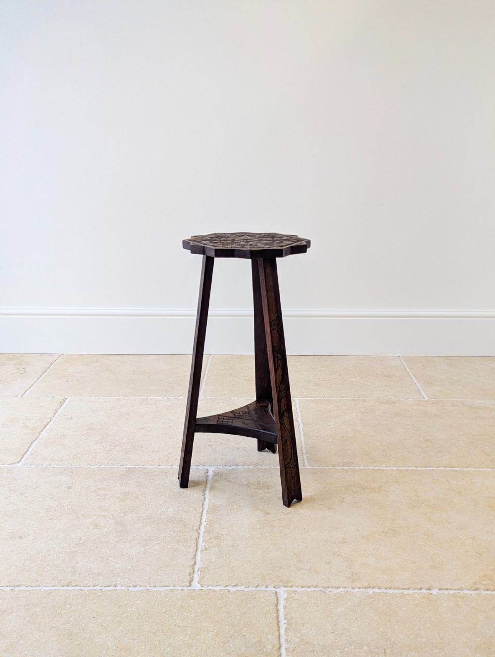 An antique dark oak three-legged occasional table featuring an octagonal carved top and triangular stretcher shelf. View IX