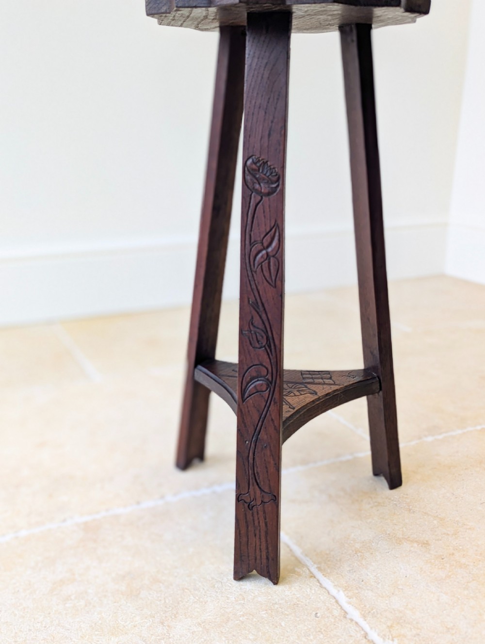 An antique dark oak three-legged occasional table featuring an octagonal carved top and triangular stretcher shelf. View X