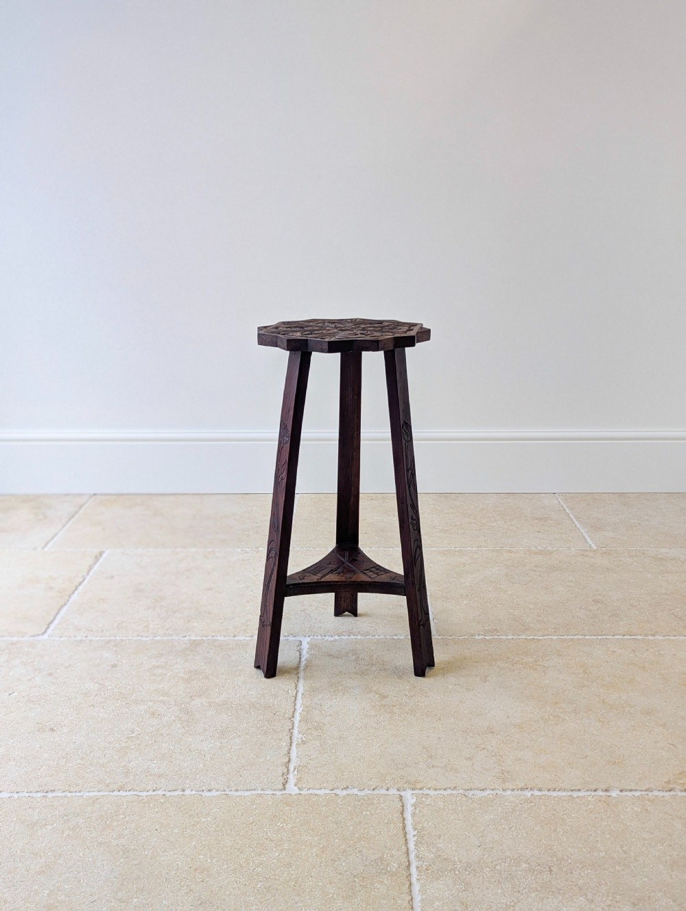 An antique dark oak three-legged occasional table featuring an octagonal carved top and triangular stretcher shelf. View XIII