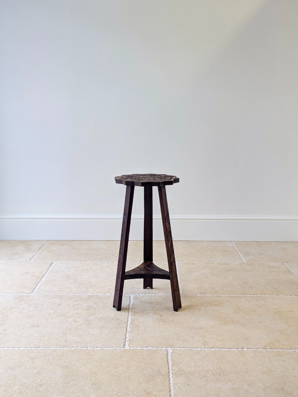 An antique dark oak three-legged occasional table featuring an octagonal carved top and triangular stretcher shelf. View XV