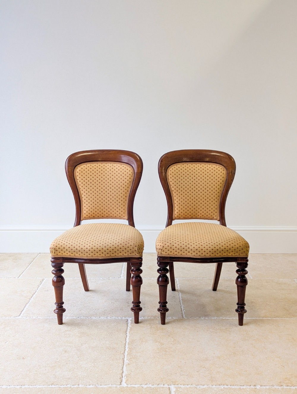 A pair of antique Victorian walnut side chairs with curved backframes, turned front legs, and patterned yellow fabric upholstery. View II
