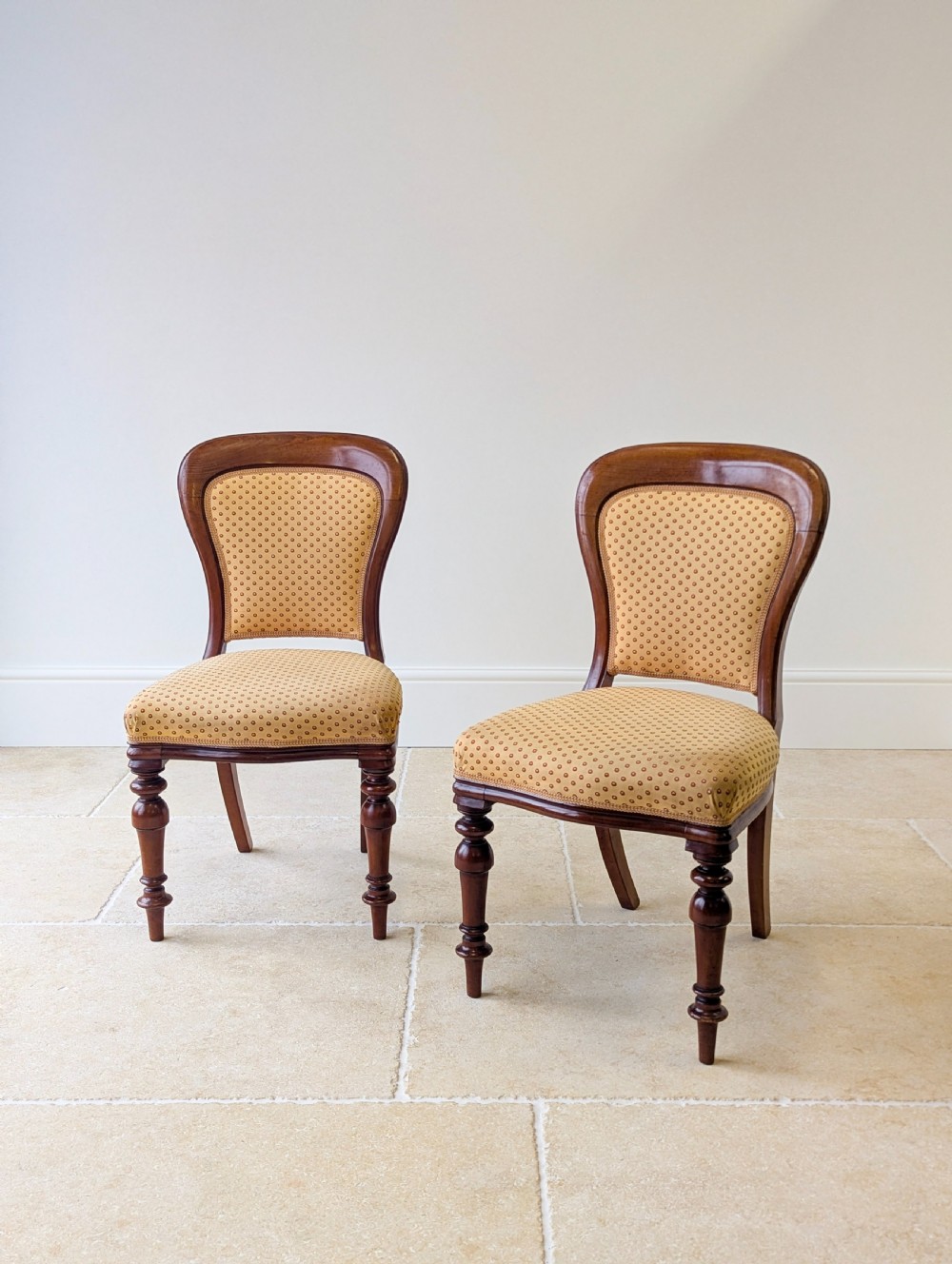 A pair of antique Victorian walnut side chairs with curved backframes, turned front legs, and patterned yellow fabric upholstery. View III
