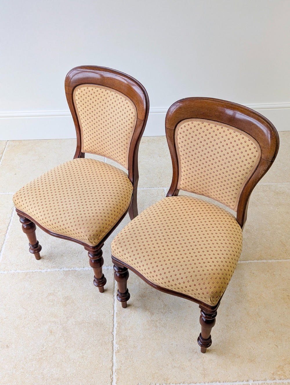 A pair of antique Victorian walnut side chairs with curved backframes, turned front legs, and patterned yellow fabric upholstery. View IV