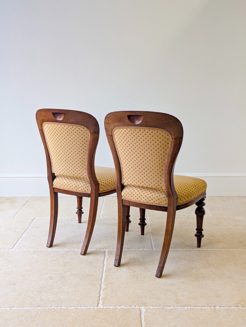 A pair of antique Victorian walnut side chairs with curved backframes, turned front legs, and patterned yellow fabric upholstery. View VII