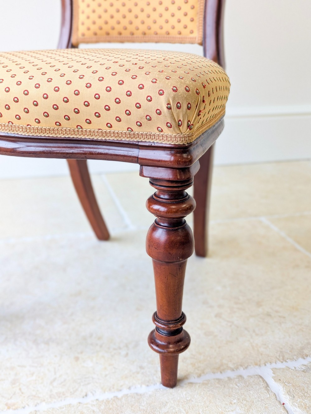 A pair of antique Victorian walnut side chairs with curved backframes, turned front legs, and patterned yellow fabric upholstery. View IX