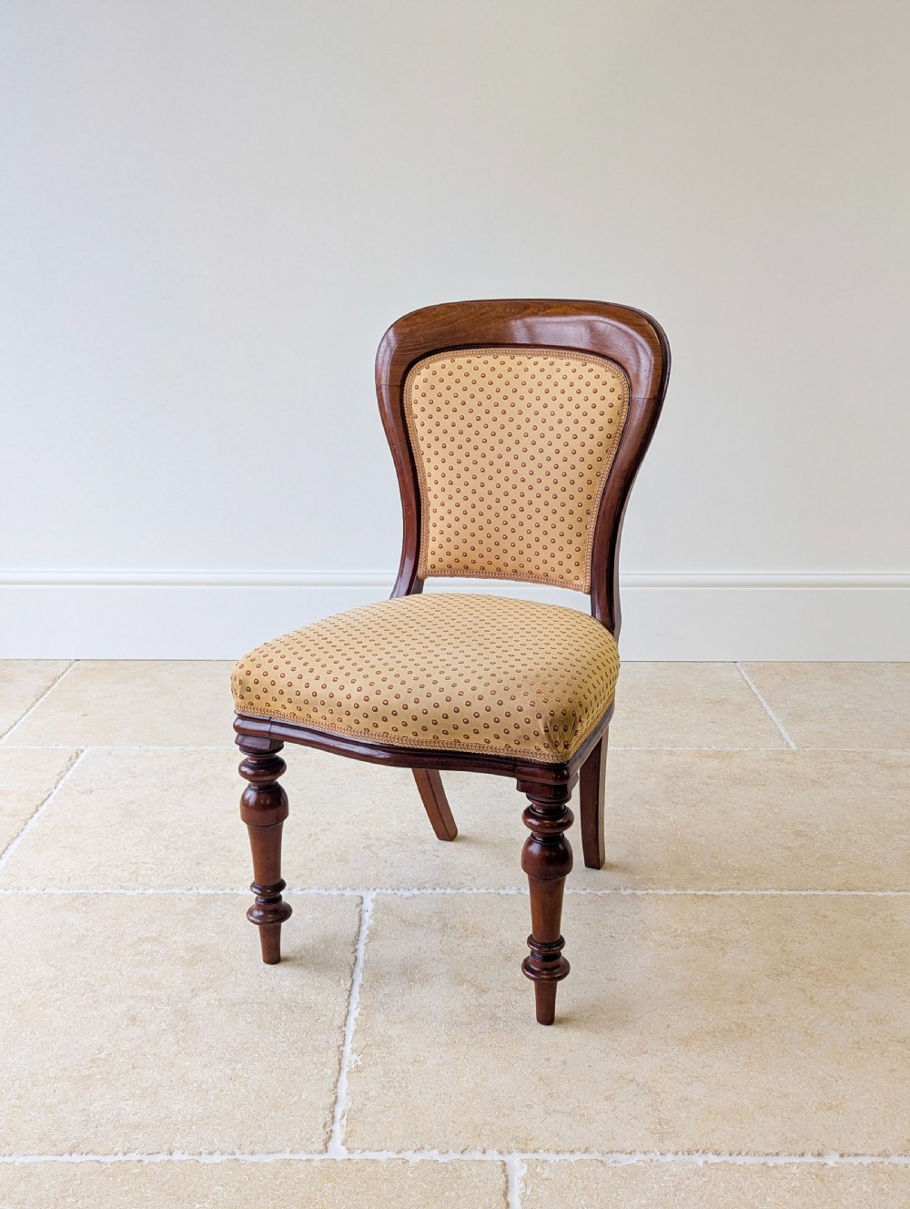 A pair of antique Victorian walnut side chairs with curved backframes, turned front legs, and patterned yellow fabric upholstery. View XII