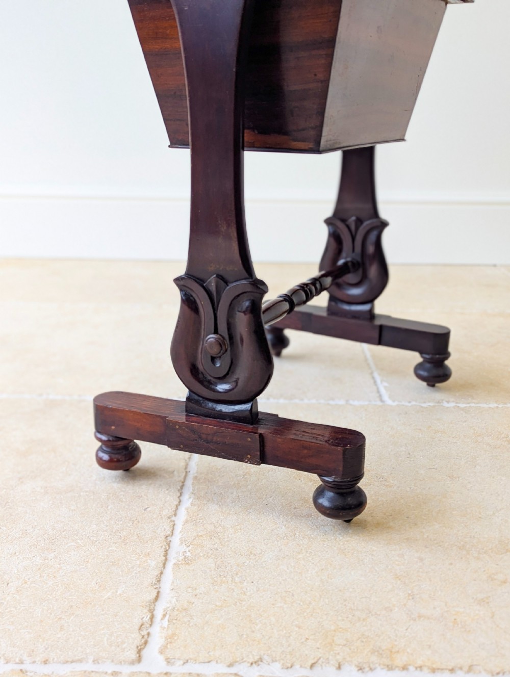 A late 19th-century Victorian mahogany sewing table featuring a top drawer with circular turned wooden handles over a deep tapered work bin, raised on scrolled lyre side supports, a turned stretcher, and castors. View VII