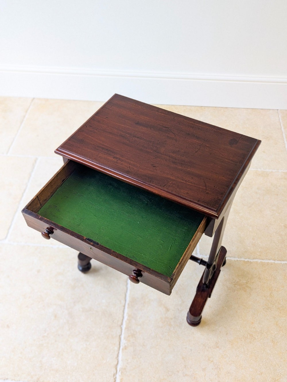 A late 19th-century Victorian mahogany sewing table featuring a top drawer with circular turned wooden handles over a deep tapered work bin, raised on scrolled lyre side supports, a turned stretcher, and castors. View XI