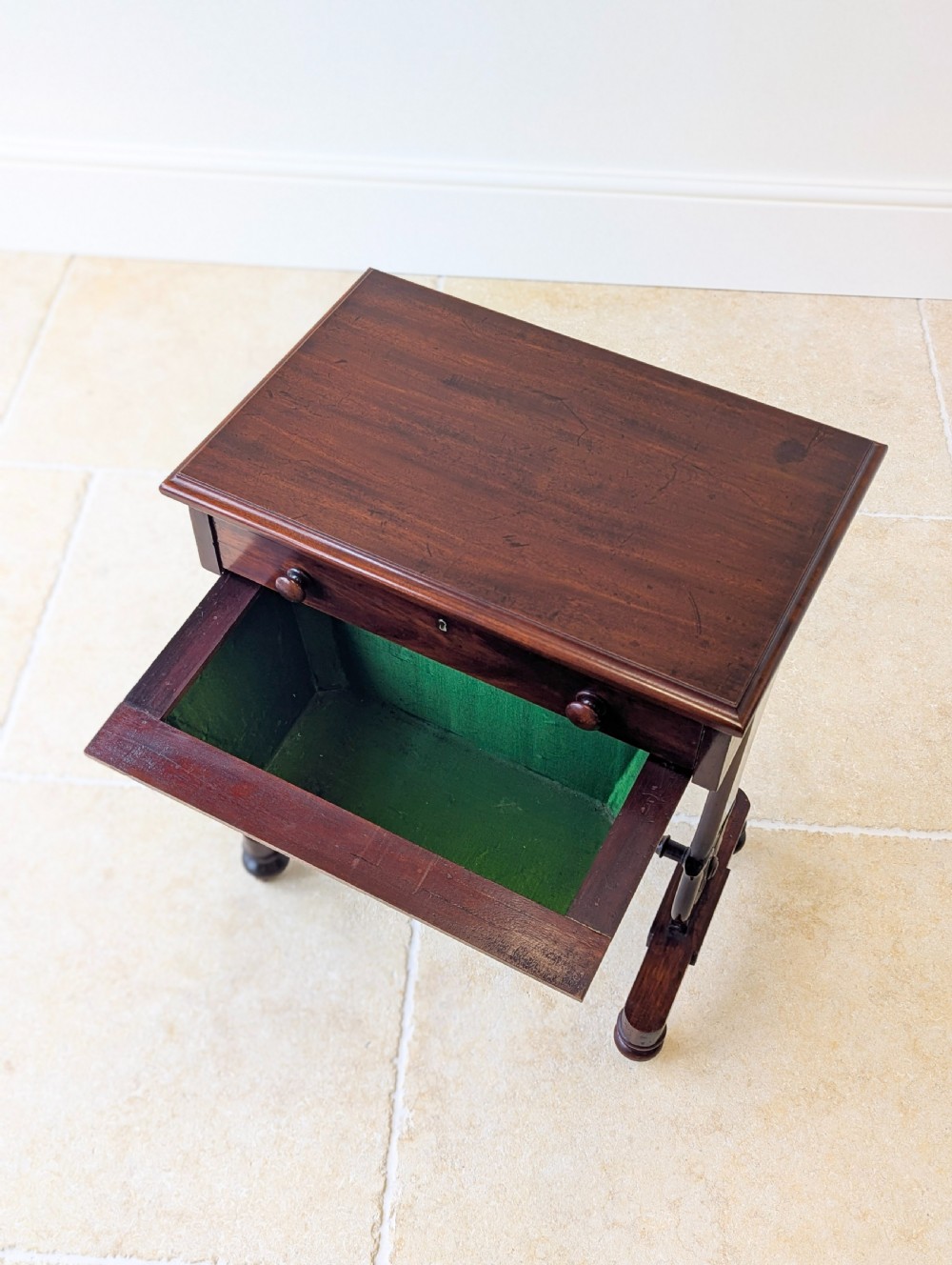 A late 19th-century Victorian mahogany sewing table featuring a top drawer with circular turned wooden handles over a deep tapered work bin, raised on scrolled lyre side supports, a turned stretcher, and castors. View XV