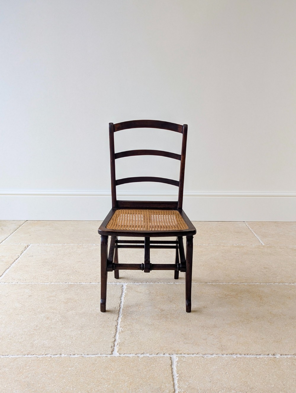 A Victorian dark wood folding campaign chair featuring a triple ladder back, a woven cane seat, and hinged folding legs. View III