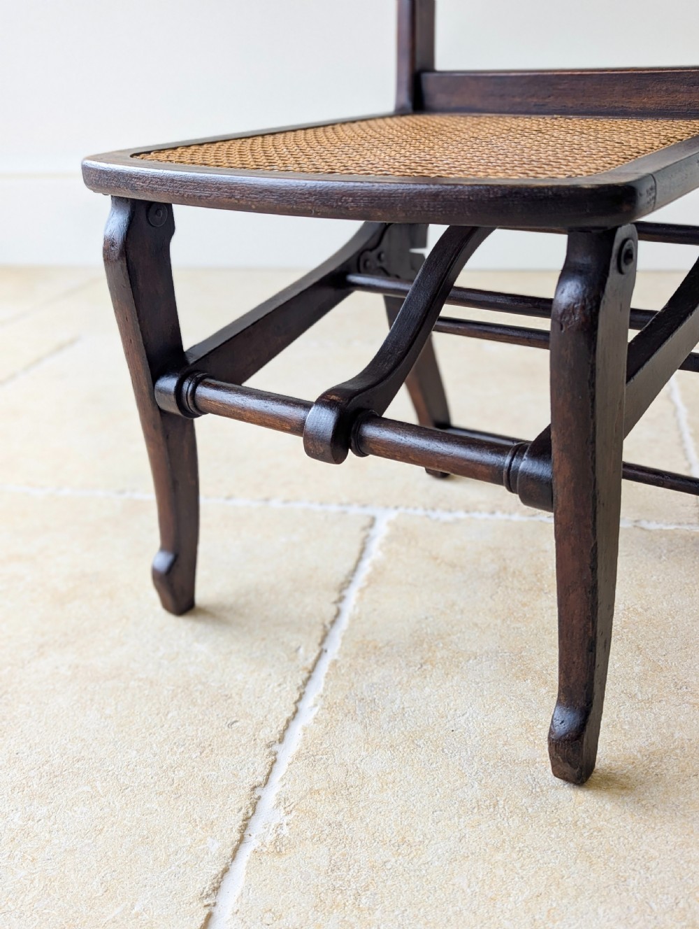 A Victorian dark wood folding campaign chair featuring a triple ladder back, a woven cane seat, and hinged folding legs. View IV