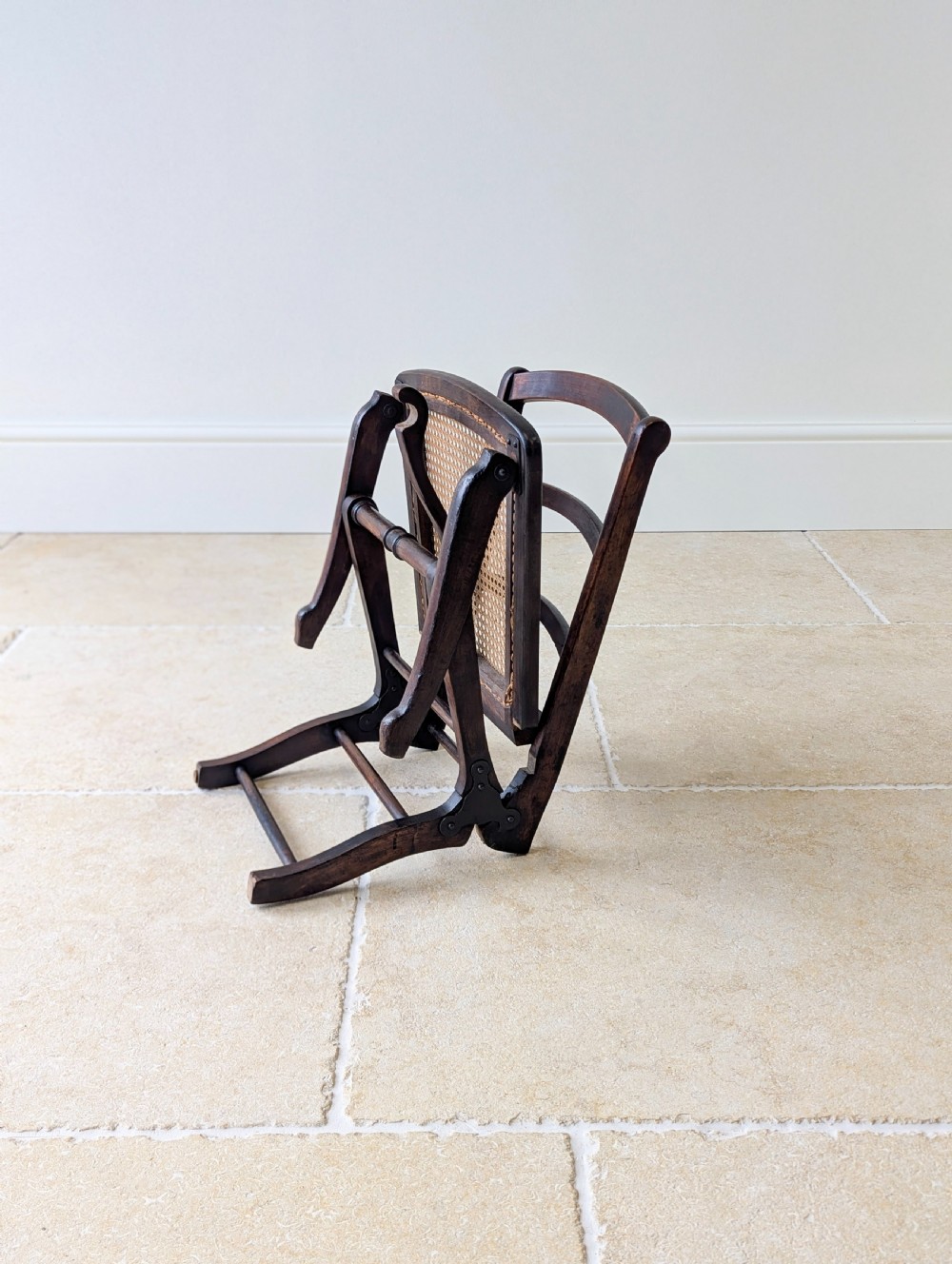 A Victorian dark wood folding campaign chair featuring a triple ladder back, a woven cane seat, and hinged folding legs. View VI