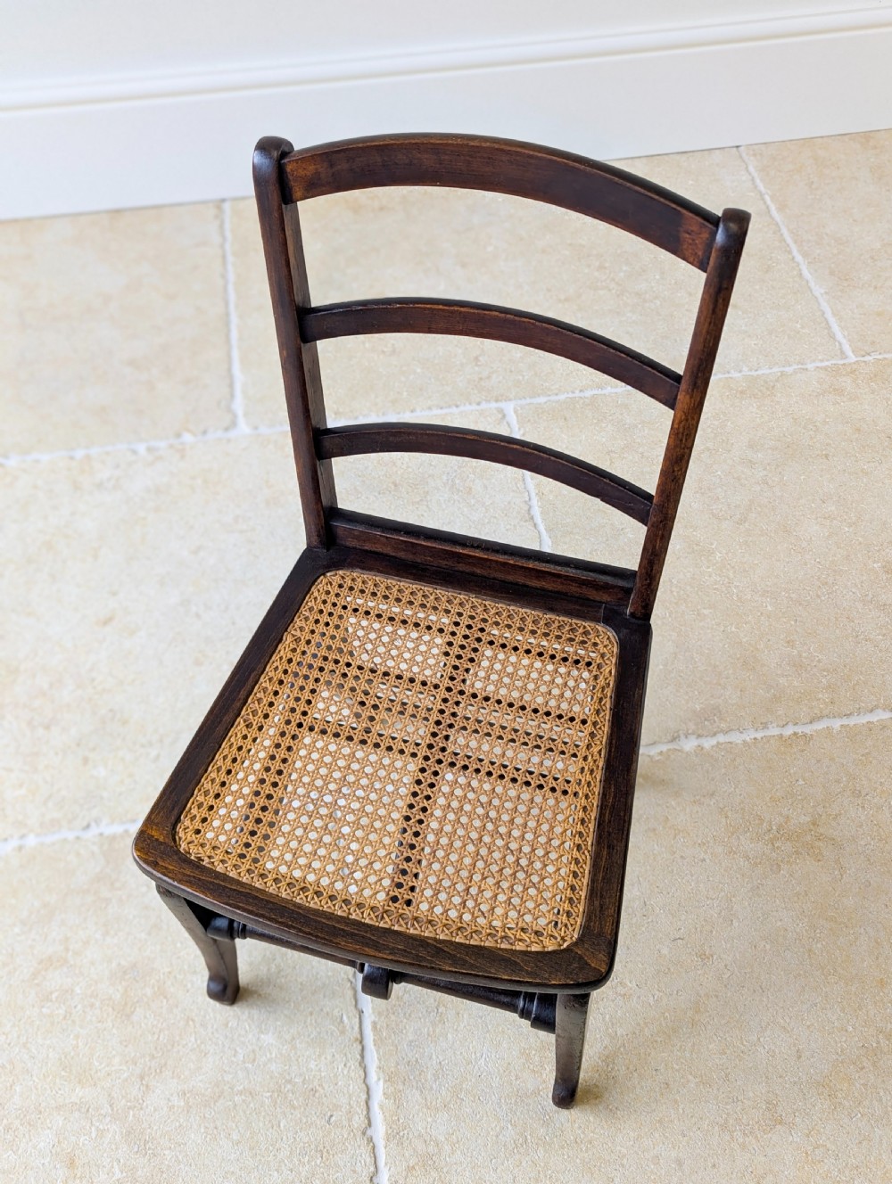 A Victorian dark wood folding campaign chair featuring a triple ladder back, a woven cane seat, and hinged folding legs. View VII