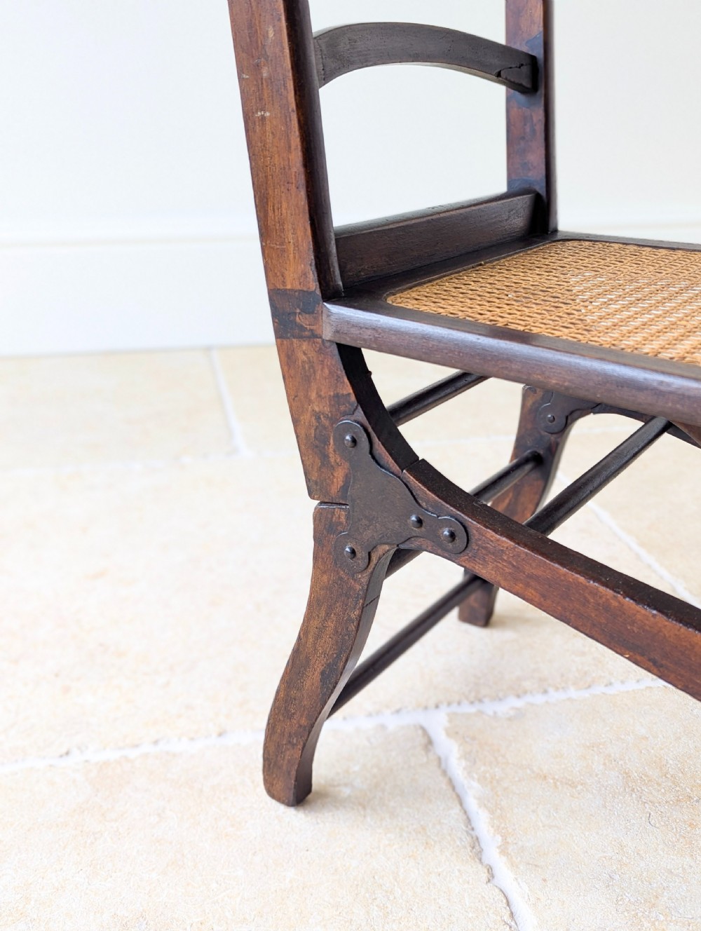 A Victorian dark wood folding campaign chair featuring a triple ladder back, a woven cane seat, and hinged folding legs. View IX