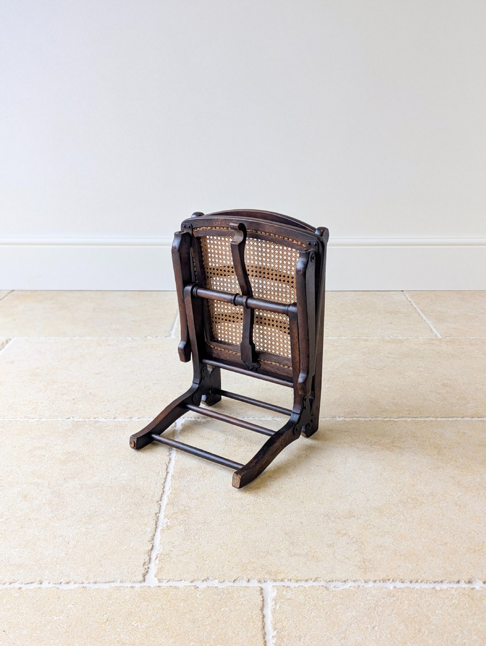 A Victorian dark wood folding campaign chair featuring a triple ladder back, a woven cane seat, and hinged folding legs. View XII
