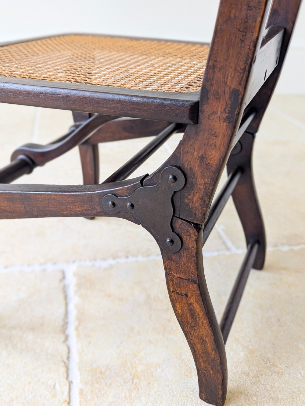 A Victorian dark wood folding campaign chair featuring a triple ladder back, a woven cane seat, and hinged folding legs. View XV