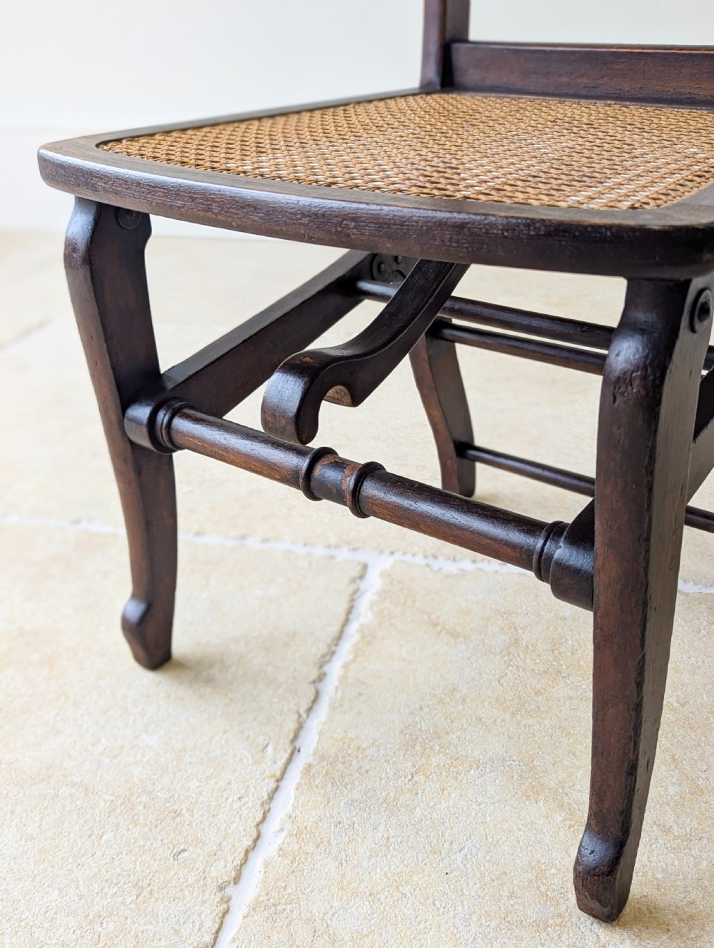 A Victorian dark wood folding campaign chair featuring a triple ladder back, a woven cane seat, and hinged folding legs. View XVI
