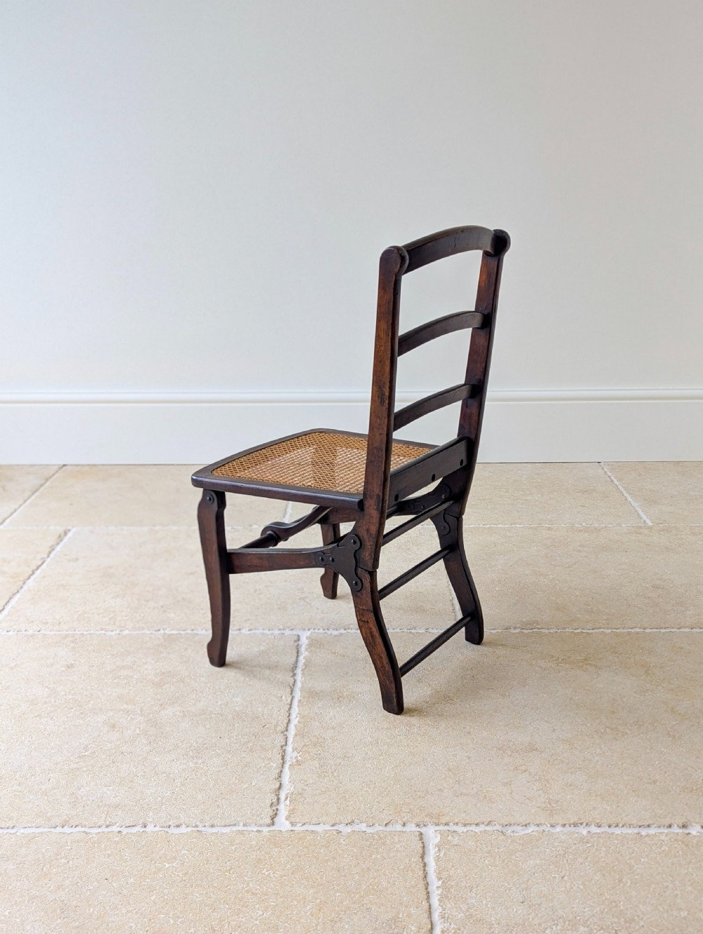 A Victorian dark wood folding campaign chair featuring a triple ladder back, a woven cane seat, and hinged folding legs. View XVIII