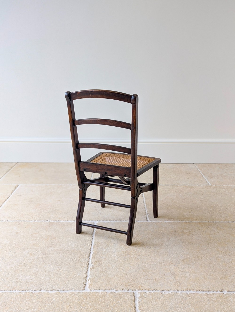 A Victorian dark wood folding campaign chair featuring a triple ladder back, a woven cane seat, and hinged folding legs. View XIX