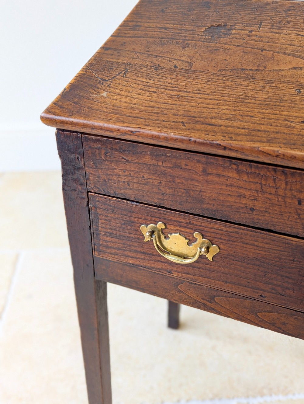 A Georgian dark elm clerks desk featuring a sloped writing surface, brass escutcheons, brass handles, and square legs. View VII