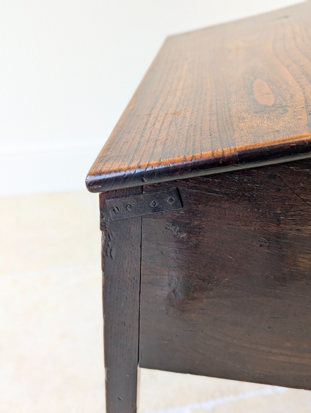 A Georgian dark elm clerks desk featuring a sloped writing surface, brass escutcheons, brass handles, and square legs. View XVIII