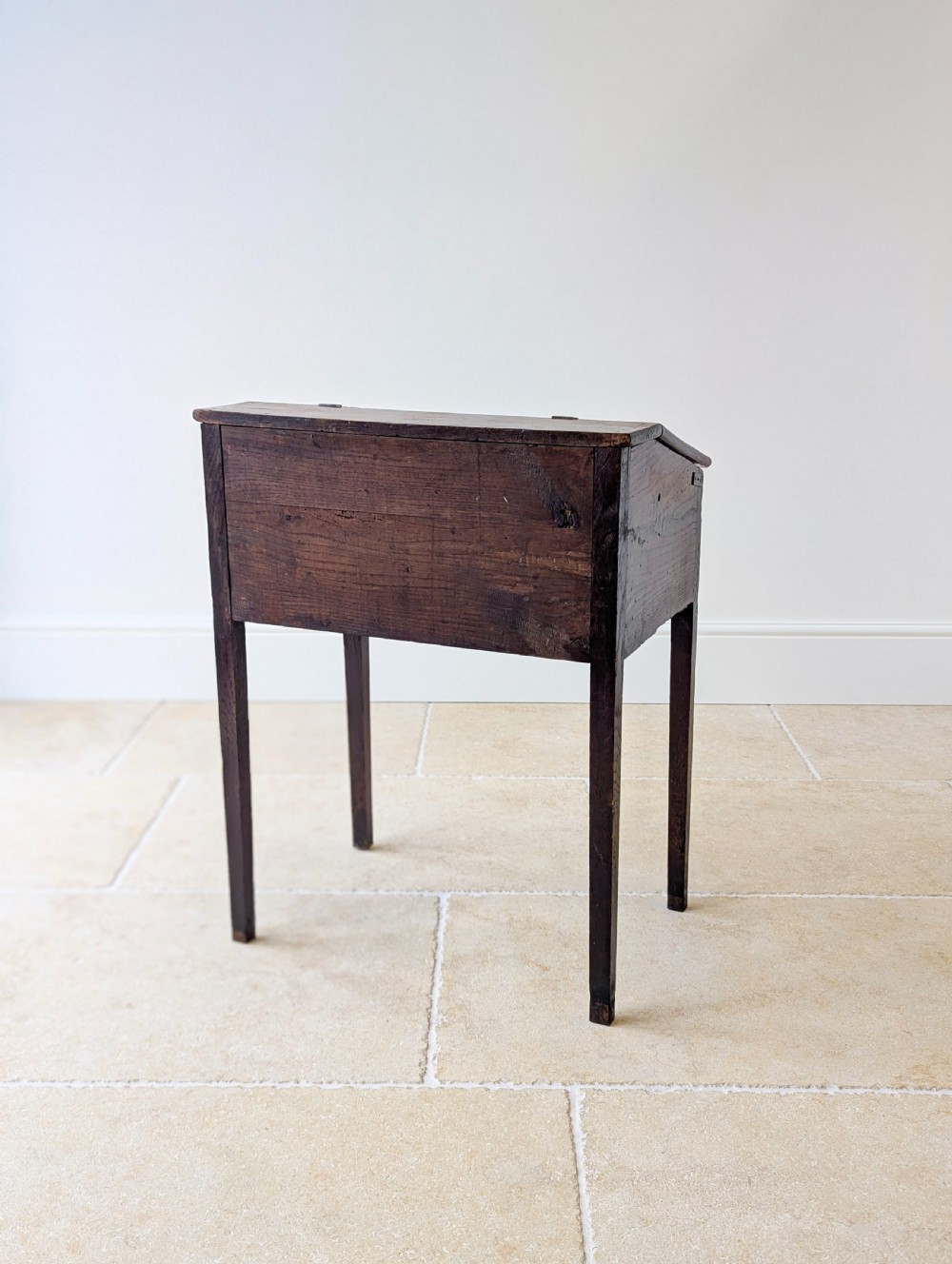 A Georgian dark elm clerks desk featuring a sloped writing surface, brass escutcheons, brass handles, and square legs. View XX