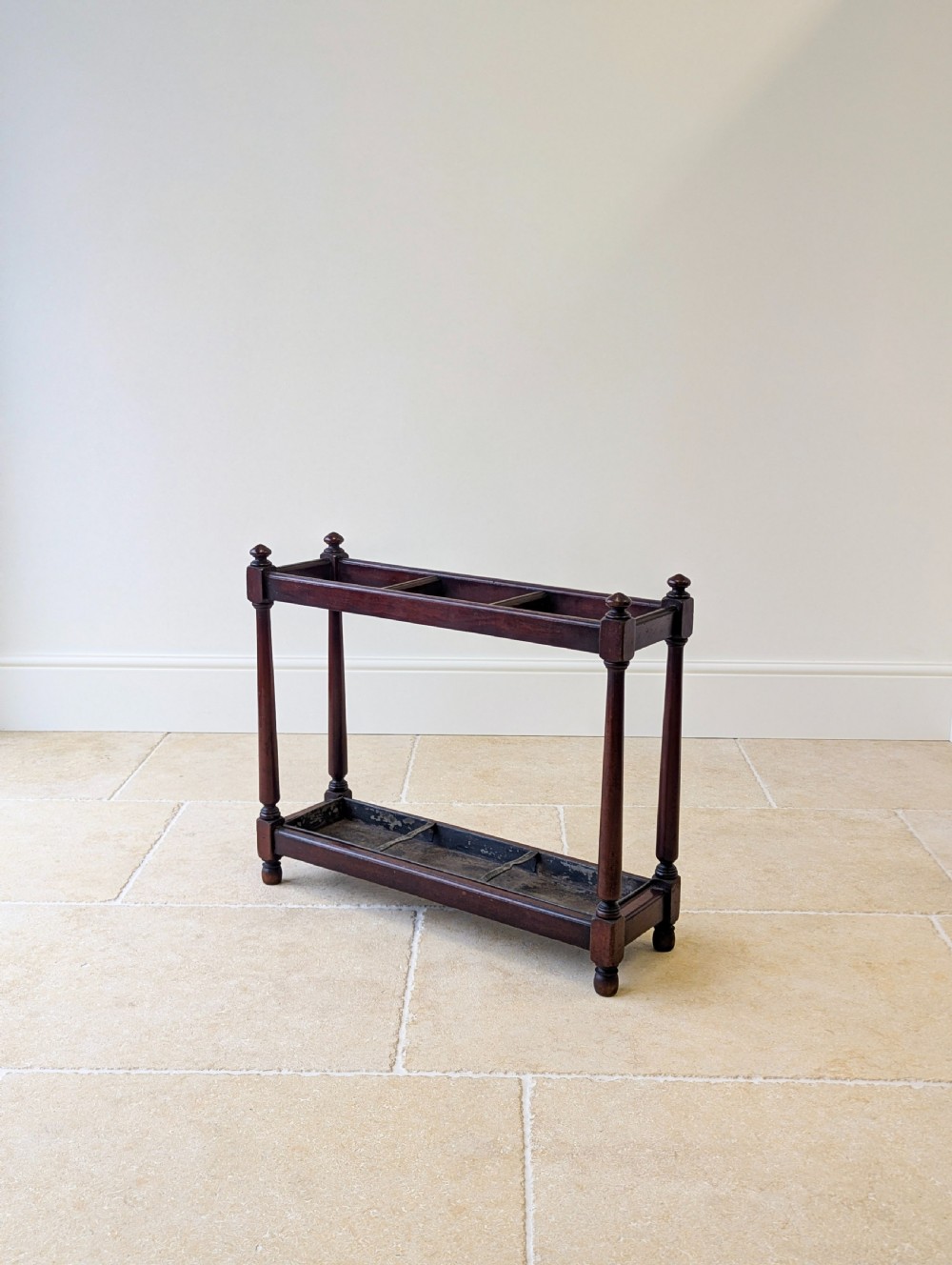 A Victorian dark mahogany stick stand featuring four turned corner supports, a partitioned upper frame, and a metal drip tray base. View II