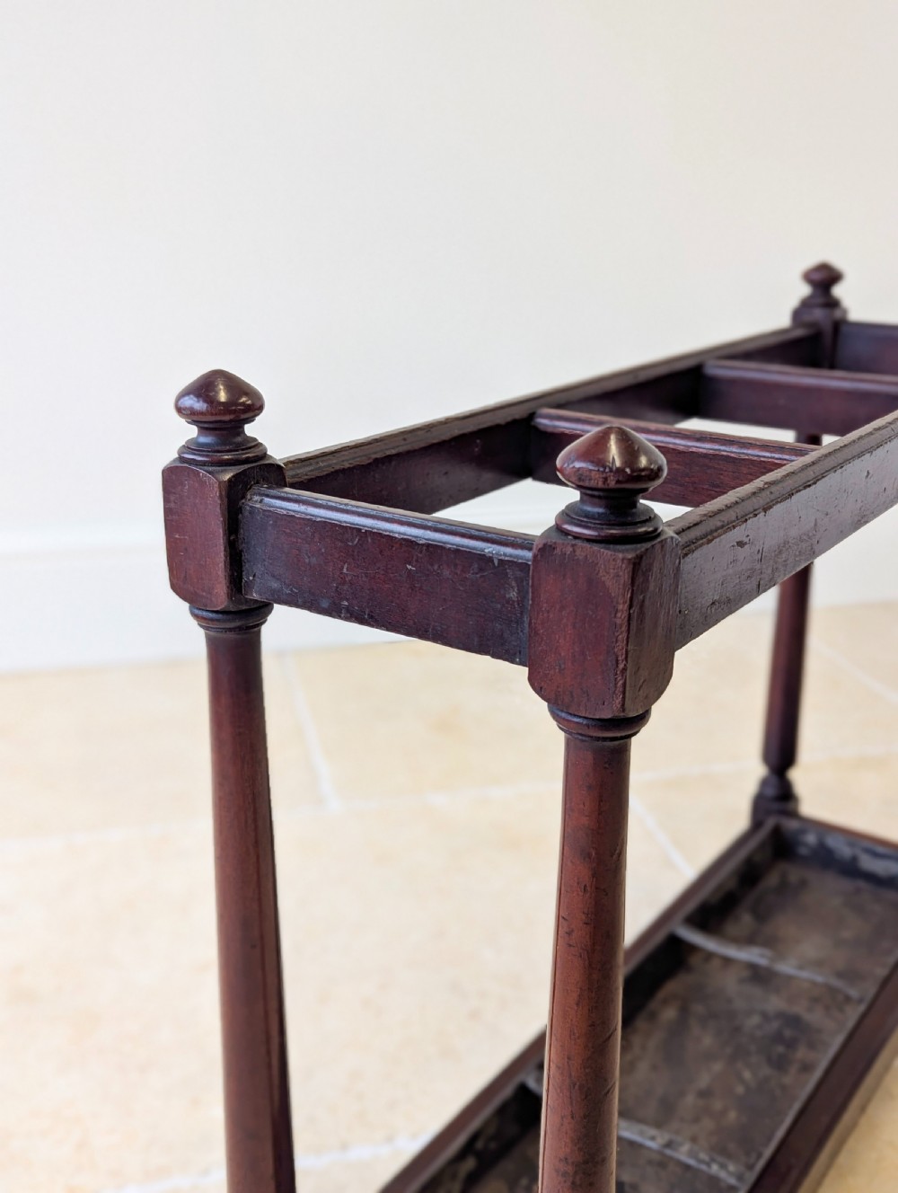 A Victorian dark mahogany stick stand featuring four turned corner supports, a partitioned upper frame, and a metal drip tray base. View III