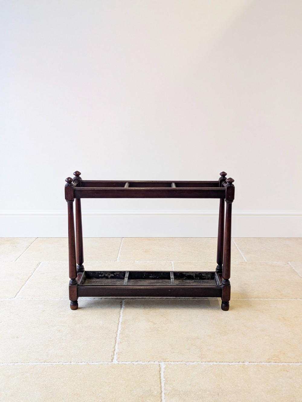 A Victorian dark mahogany stick stand featuring four turned corner supports, a partitioned upper frame, and a metal drip tray base. View IV