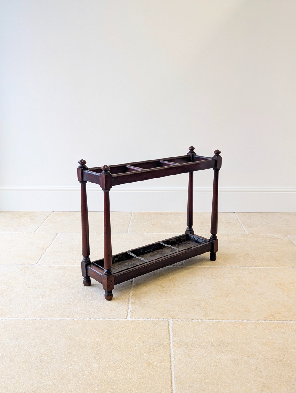 A Victorian dark mahogany stick stand featuring four turned corner supports, a partitioned upper frame, and a metal drip tray base. View VI