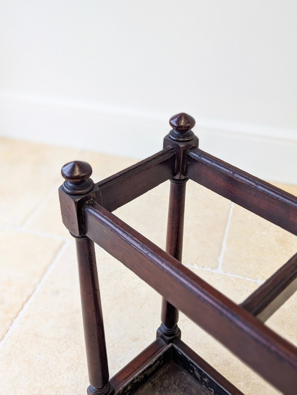 A Victorian dark mahogany stick stand featuring four turned corner supports, a partitioned upper frame, and a metal drip tray base. View IX