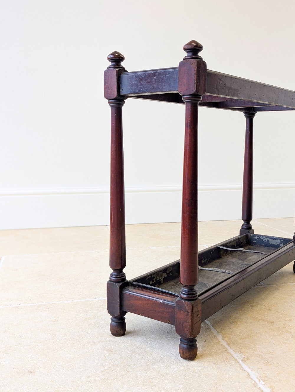 A Victorian dark mahogany stick stand featuring four turned corner supports, a partitioned upper frame, and a metal drip tray base. View XI