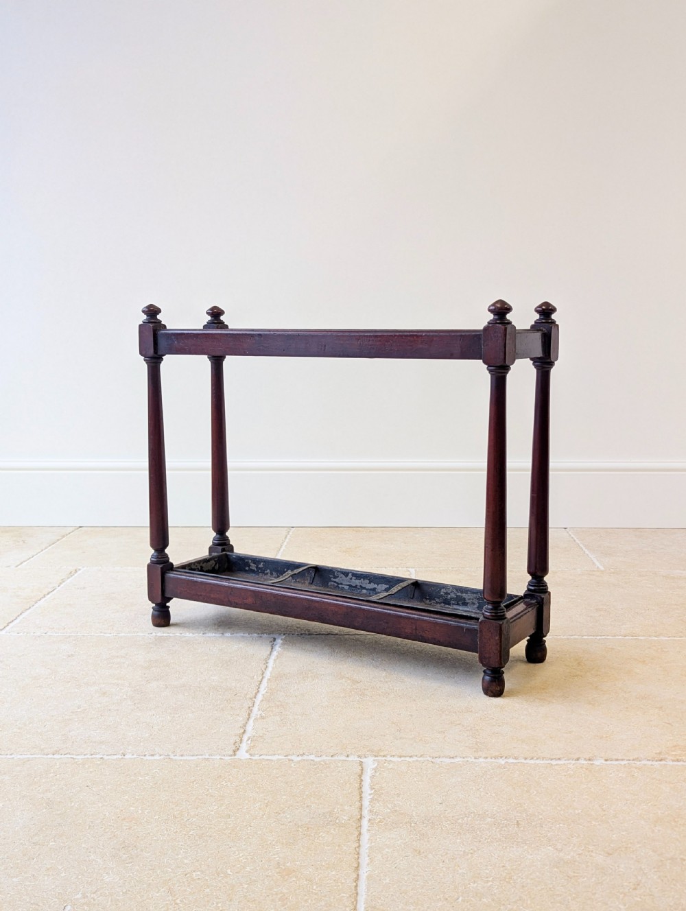 A Victorian dark mahogany stick stand featuring four turned corner supports, a partitioned upper frame, and a metal drip tray base. View XII