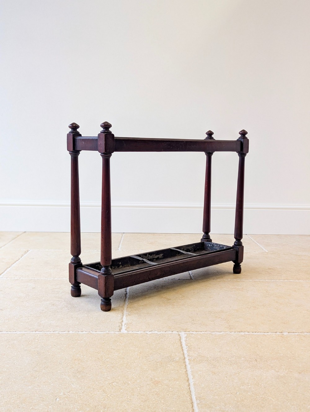 A Victorian dark mahogany stick stand featuring four turned corner supports, a partitioned upper frame, and a metal drip tray base. View XIV