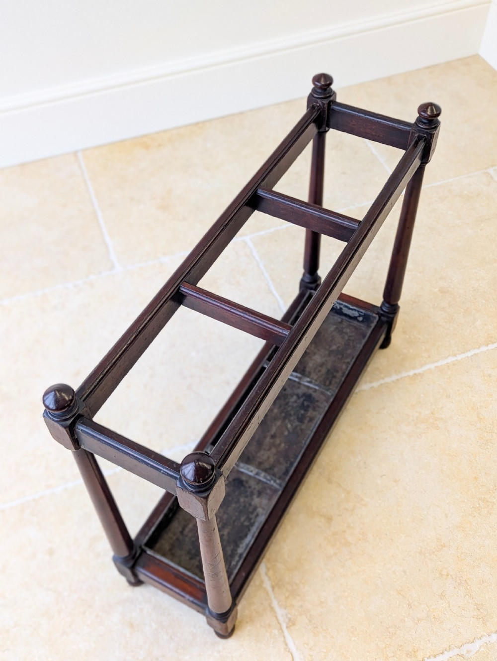 A Victorian dark mahogany stick stand featuring four turned corner supports, a partitioned upper frame, and a metal drip tray base. View XV