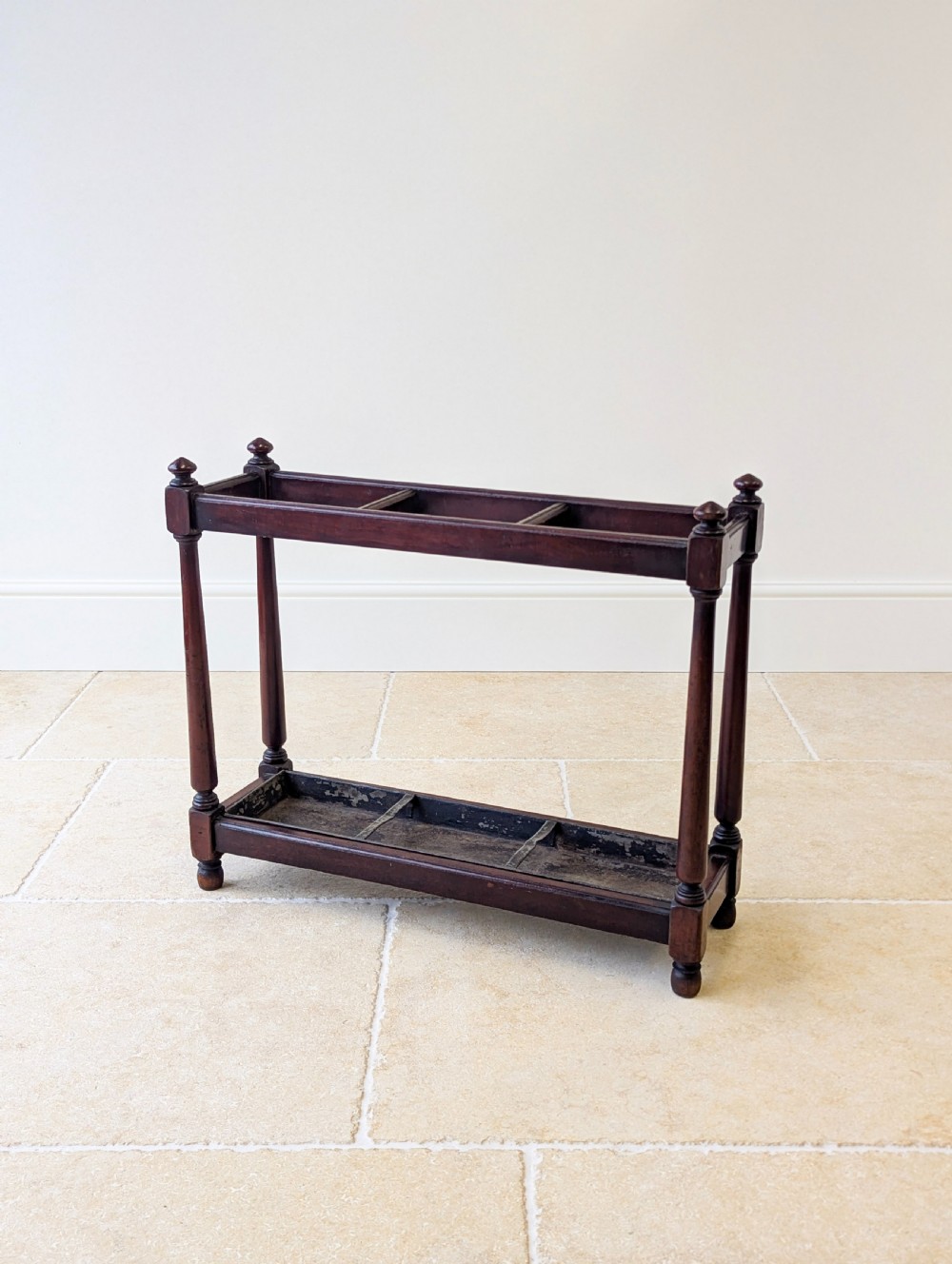 A Victorian dark mahogany stick stand featuring four turned corner supports, a partitioned upper frame, and a metal drip tray base. View XVI